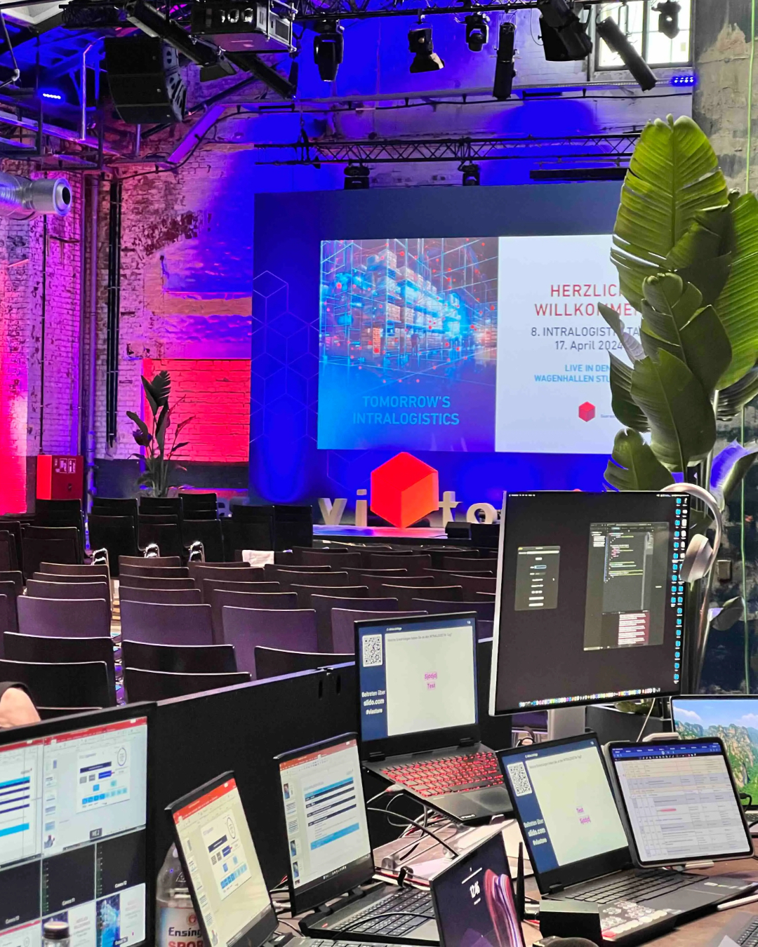 man watching a band on the stage wearing a red t-shirt and black hat.